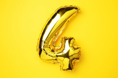 Yaratıcı düzen. Altın folyo balon numarası ve 4 haneli rakam. Doğum günü tebrik kartı. Yıldönümü konsepti. Üst Manzara. Uzayı kopyala Sarı arkaplan üzerinde zarif altın rakam. Sayısal rakam