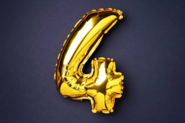 Creative layout. Golden foil balloon number and digit four 4. Birthday greeting card. Anniversary concept. Top view. Copy space. Stylish gold numeral over black background. Numerical digit
