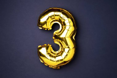 Creative layout. Golden foil balloon number and digit three 3. Birthday greeting card. Anniversary concept. Top view. Copy space. Stylish gold numeral over black background. Numerical digit
