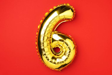 Yaratıcı düzen. Altın folyo balon numarası ve altı haneli sayı. Doğum günü tebrik kartı. Yıldönümü konsepti. Üst Manzara. Uzayı kopyala Kırmızı zemin üzerinde zarif altın rakam. Sayısal rakam