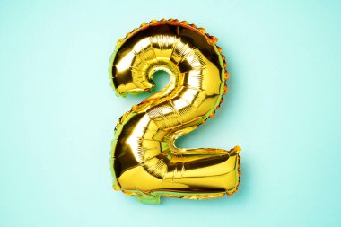Yaratıcı düzen. Altın folyo balon numarası ve 2 haneli rakam. Doğum günü tebrik kartı. Yıldönümü konsepti. Üst Manzara. Uzayı kopyala Mavi arka planda zarif altın rakamı. Sayısal rakam