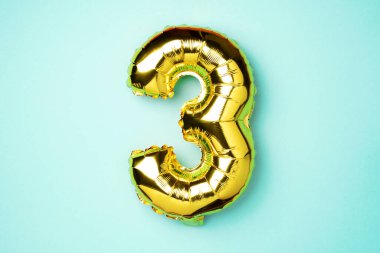 Yaratıcı düzen. Altın folyo balon numarası ve 3 haneli rakam. Doğum günü tebrik kartı. Yıldönümü konsepti. Üst Manzara. Uzayı kopyala Mavi arka planda zarif altın rakamı. Sayısal rakam