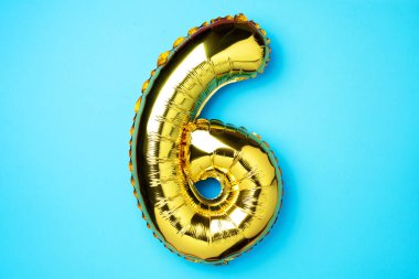 Yaratıcı düzen. Altın folyo balon numarası ve altı haneli sayı. Doğum günü tebrik kartı. Yıldönümü konsepti. Üst Manzara. Uzayı kopyala Mavi arka planda zarif altın rakamı. Sayısal rakam