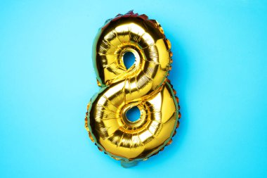 8 Mart. Mutlu Kadınlar Günü. Yaratıcı düzen. Altın folyo balon numarası ve rakam sekiz sekiz. Doğum günü tebrik kartı. Yıldönümü konsepti. Üst Manzara. Altın sayı mavi arkaplandan üstündür. Sayısal rakam
