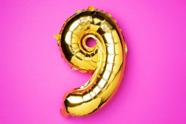 Yaratıcı düzen. Altın folyo balon numarası ve 99. rakam. Doğum günü tebrik kartı. Yıldönümü konsepti. Üst Manzara. Uzayı kopyala Pembe arka planda zarif altın rakamı. Sayısal rakam