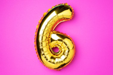 Yaratıcı düzen. Altın folyo balon numarası ve altı haneli sayı. Doğum günü tebrik kartı. Yıldönümü konsepti. Üst Manzara. Uzayı kopyala Pembe arka planda zarif altın rakamı. Sayısal rakam