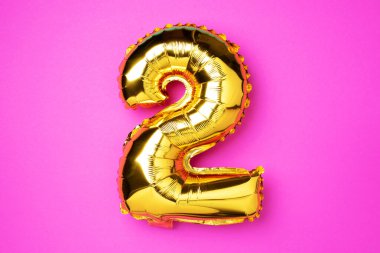 Yaratıcı düzen. Altın folyo balon numarası ve 2 haneli rakam. Doğum günü tebrik kartı. Yıldönümü konsepti. Üst Manzara. Uzayı kopyala Pembe arka planda zarif altın rakamı. Sayısal rakam