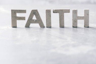 Word FAITH made with cement letters on grey marble background. Copy space. Biblical, spiritual or christian reminder.