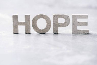 Word HOPE made with cement letters on grey marble background. Copy space. Biblical, spiritual or christian reminder.