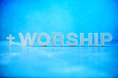 Word Worship made with cement letters on blue marble background. Copy space. Biblical, spiritual or christian reminder. Good friday, Easter day in church. Christian music concert, Sunday service.