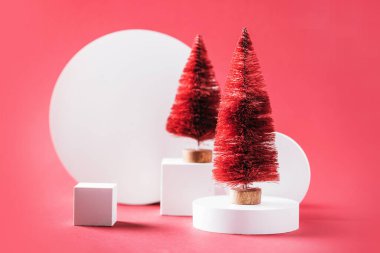 White product stand, zero waste fir-trees in minimal style on red background. New Year, Christmas mock up background with geometric podium for product display. Copy space for your design.