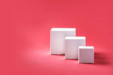 Abstract empty geometric shape podium for product on pastel red background. Copy space. White cube on pink backdrop. Pedestal template for advertising. Trendy minimal concept. Mock up.