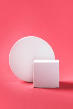 Abstract empty geometric shape podium for product on pastel red background. Copy space. White cube on pink backdrop. Pedestal template for advertising. Trendy minimal concept. Mock up.