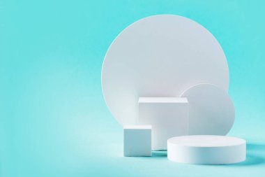 White geometric shapes podium for product display on blue background. Monochrome stage, stand for product promotion in minimal style. Copy space for your design. Banner.