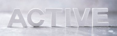 Word ACTIVE made with cement letters on grey marble background. Copy space. Business concept.