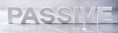 Word PASSIVE made with cement letters on grey marble background. Copy space. Business concept.