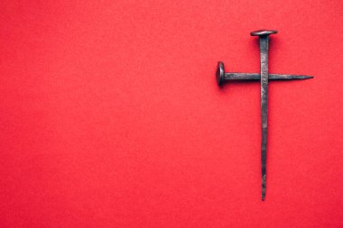 Cross made with rusty nails and drops of blood on red background. Copy space. Good Friday, Easter day. Christian backdrop. Biblical faith, gospel, salvation concept. Crucifixion of Jesus Christ.