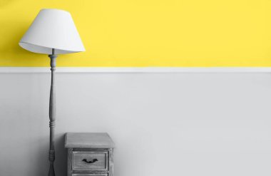 2021 yılının modaya uygun rengini gösteriyor. Aydınlatıcı sarı ve nihai gri. Duotone. Pastel duvar arka planında yer lambası. Renk Psikolojisi. Minimalist oda içi. Depresyon tedavisi.