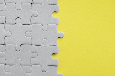 2021 yılının modaya uygun rengini gösteriyor. Aydınlatıcı sarı ve nihai gri. Duotone. Çoklu gri yapboz parçaları sarı arkaplanda tek bir parça olmadan bir araya getirildi.