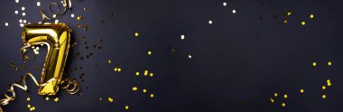 Altın folyo balon numarası ve 7 haneli rakam. Doğum günü tebrik kartı. Yıldönümü kutlaması. Pankart. Uzayı kopyala Şık altın rakamlı, açık renkli, parlak, siyah arkaplan. Sayısal rakam