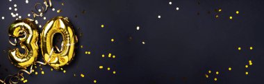 Altın folyo balon numarası, sayı 30. Doğum günü tebrik kartında 30 yazılıydı. Yıldönümü kutlaması. Pankart. Altın rakamlı, siyah arkaplan. Sayısal rakam, ışık bokeh, parıltı