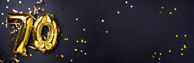 Altın folyo balon numarası, 70. 70 yazısıyla birlikte doğum günü tebrik kartı. Yıldönümü kutlaması. Pankart. Altın rakamlı, siyah arkaplan. Sayısal rakam, ışık bokeh, parıltı