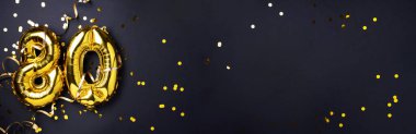 Altın folyo balon numarası, 80 haneli. 80 yazılı doğum günü tebrik kartı var. Yıldönümü kutlaması. Pankart. Altın rakamlı, siyah arkaplan. Sayısal rakam, ışık bokeh, parıltı