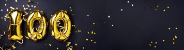 Altın folyo balon numarası, 100 haneli rakam. Doğum günü tebrik kartında 100 yazılıydı. Yıldönümü kutlaması. Pankart. Altın rakamlı, siyah arkaplan. Sayısal rakam, ışık bokeh, parıltı.