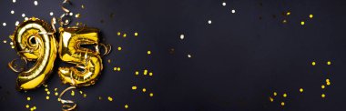 Altın folyo balon numarası, doksan beş. Doğum günü tebrik kartında 95 yazılıydı. Yıldönümü kutlaması. Pankart. Altın rakamlı, siyah arkaplan. Sayısal rakam, ışık bokeh, parıltı.