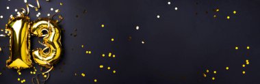 Altın folyo balon numarası, 13 numara. Doğum günü tebrik kartı, 13. yazı. Yıldönümü kutlaması. Pankart. Şık altın rakamlı, açık renkli, parlak, siyah arkaplan. Sayısal rakam.