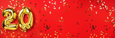 Altın folyo balon numarası, 20 haneli. Üzerinde 20 yazan doğum günü tebrik kartı. Yıldönümü kutlaması. Pankart. Altın rakamlı, kırmızı arkaplan. Sayısal rakam, ışık bokeh, parıltı