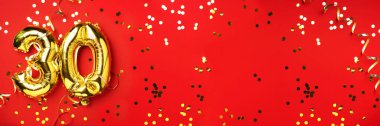 Altın folyo balon numarası, sayı 30. Doğum günü tebrik kartında 30 yazılıydı. Yıldönümü kutlaması. Pankart. Altın rakamlı, kırmızı arkaplan. Sayısal rakam, ışık bokeh, parıltı