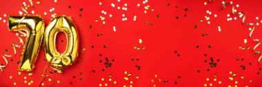 Altın folyo balon numarası, 70. 70 yazısıyla birlikte doğum günü tebrik kartı. Yıldönümü kutlaması. Pankart. Altın rakamlı, kırmızı arkaplan. Sayısal rakam, ışık bokeh, parıltı