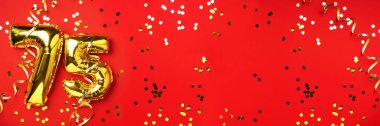 Altın folyo balon numarası, rakam 75. Doğum günü tebrik kartında 75 yazılıydı. Yıldönümü kutlaması. Pankart. Altın rakamlı, kırmızı arkaplan. Sayısal rakam, ışık bokeh, parıltı.