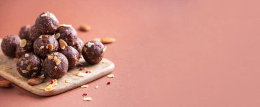 Sağlıklı ev yapımı paleo, yuvarlanmış yulaf, fındık, hurma ve badem gevreği ve kurutulmuş ahududu içeren protein çikolata enerji toplarıyla savaş. Çiğ vejetaryen tatlıları. Şekersiz, glütensiz. Banner, boşluğu kopyala.