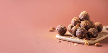 Kurutulmuş meyve ve fındıklı ev yapımı vejetaryen çikolatalı trüf mantarları ahşap arka planda karıştırılır. Sağlıklı tatlılar. Enerji dolu vejetaryen toplar, hurma, kakao ve badem gevreği. Banner, boşluğu kopyala.