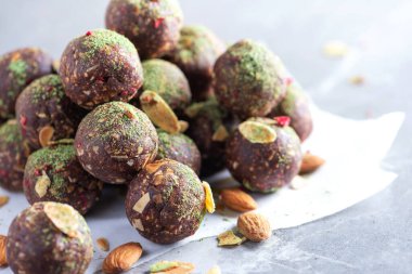 Çiğ enerji topları ve gri arka planda kibrit çay tozu. Çiğ vejetaryen, vejetaryen tatlılar. Şekersiz, glütensiz, laktozsuz.