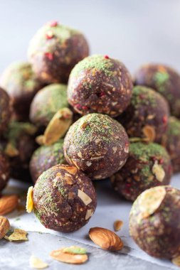 Çiğ enerji topları ve gri arka planda kibrit çay tozu. Çiğ vejetaryen, vejetaryen tatlılar. Şekersiz, glütensiz, laktozsuz.