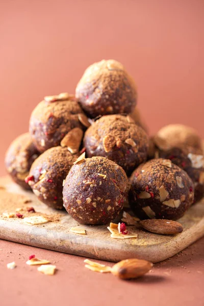 Sağlıklı ev yapımı paleo, yuvarlanmış yulaf, fındık, hurma ve badem gevreği ve kurutulmuş ahududu içeren protein çikolata enerji toplarıyla savaş. Çiğ vejetaryen tatlıları. Şekersiz, glütensiz, laktozsuz.