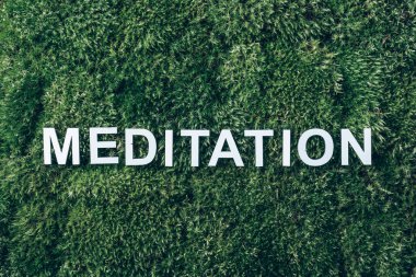 Word Meditation on moss, green grass background. Top view. Copy space. Banner. Biophilia trend. Nature backdrop. Peace of Mind, health concept. clipart