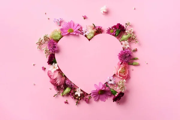 Diseño creativo con flores de color rosa, corazón de papel sobre fondo pastel perforado. Vista superior, cama plana. Concepto de primavera, verano o jardín. Regalo para el día de la mujer —  Fotos de Stock