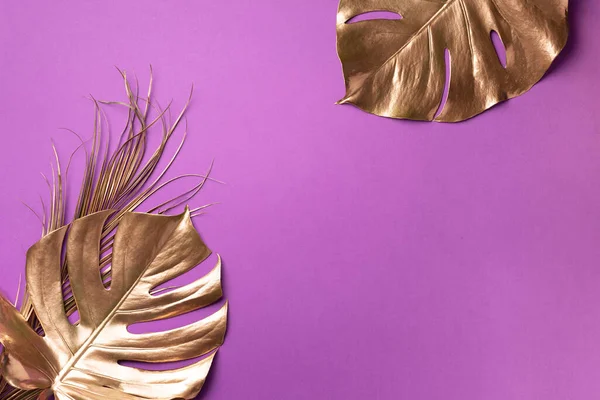 Folha de monstera tropical dourada sobre fundo violeta com espaço de cópia. Vista superior. Deitado. Layout criativo. Conceito de verão exótico em estilo mínimo — Fotografia de Stock