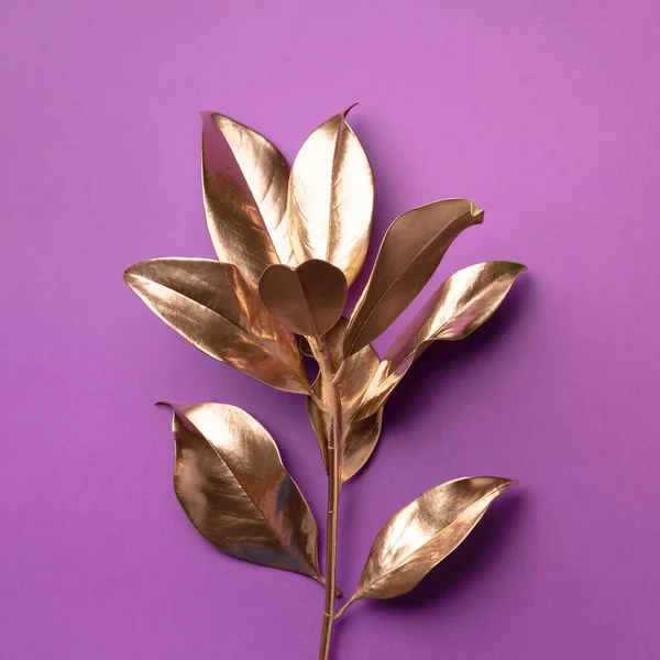 Concept floral de style minimal. Tendance estivale exotique. Feuilles tropicales dorées et branche sur fond violet. Design brillant et scintillant, concept de mode. Images De Stock Libres De Droits