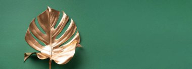 En az düzeyde egzotik yaz trendi. Pastel yeşil arka planda altın tropikal palmiye yaprağı. Parlak ve ışıltılı tasarım, moda konsepti.