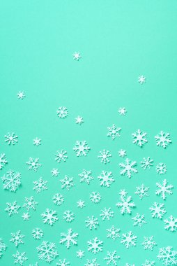 Kış kompozisyonu. Noel, yeni yıl konsepti. Üst Manzara. Düz yatıyordu. Yeşil arka planda beyaz kar tanelerinden oluşan kış deseni.
