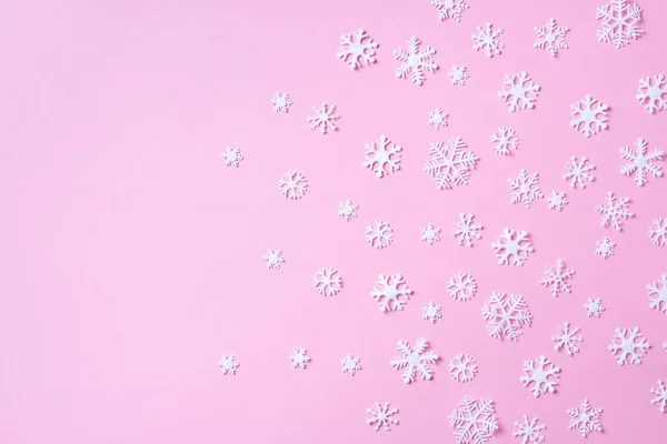 Composizione invernale. Natale, nuovo concetto di anno. Vista dall'alto. Piatto. Modello invernale fatto di fiocchi di neve bianchi su sfondo rosa. — Foto Stock