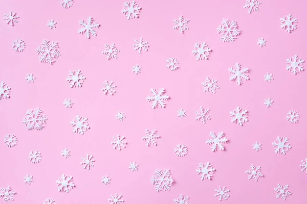 Winterpatroon gemaakt van witte sneeuwvlokken op roze achtergrond. Bovenaanzicht. Plat gelegd. Wintercompositie. Kerstmis, nieuwjaarsconcept. — Stockfoto