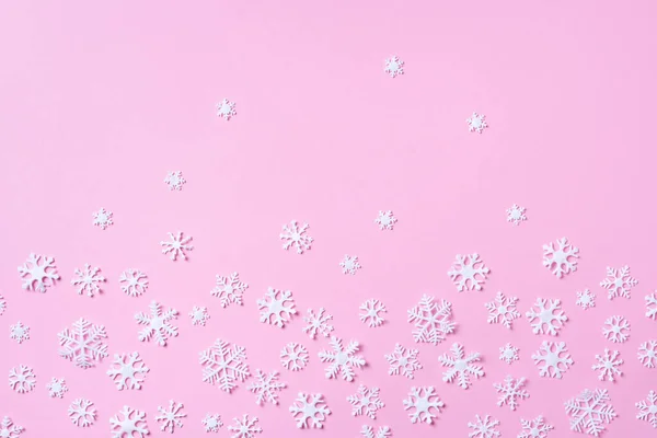 Patrón de invierno hecho de copos de nieve blancos sobre fondo rosa. Vista superior. Acostado. Composición de invierno. Navidad, concepto de año nuevo. —  Fotos de Stock