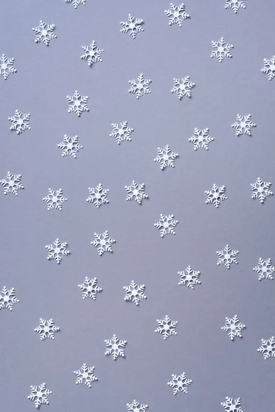 Modello invernale realizzato con fiocchi di neve bianchi su sfondo grigio. Vista dall'alto. Piatto. Composizione invernale. Natale, nuovo concetto di anno. — Foto Stock
