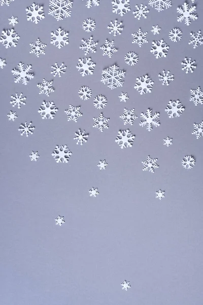 Téli kompozíció. Karácsony, újévi koncepció. Első látásra. Lapos fekvés. Téli minta készült fehér hópelyhek szürke alapon. — Stock Fotó